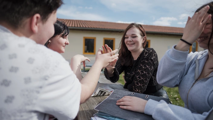 Mehrere Jugendliche sitzen beim Lernen zusammen im Freien