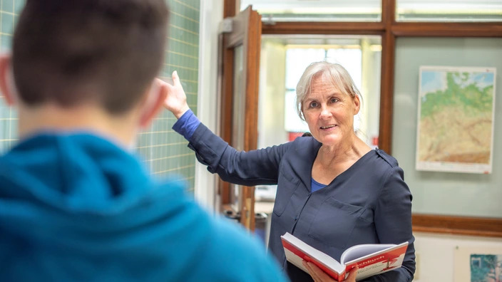 Lehrerin erklärt einem Schüler etwas an der Tafel